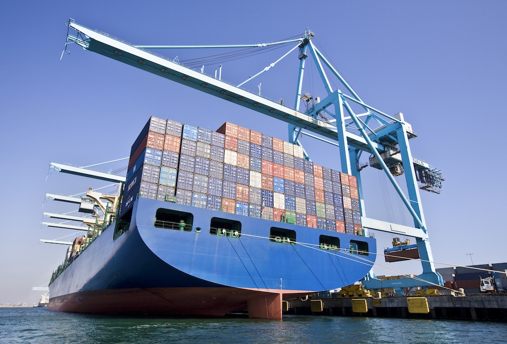 a boat carrying cargo with cranes for lifting up c